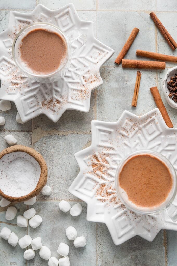 Countertop set with snowflake plates and mugs of hot cocoa in double-walled glass mugs.