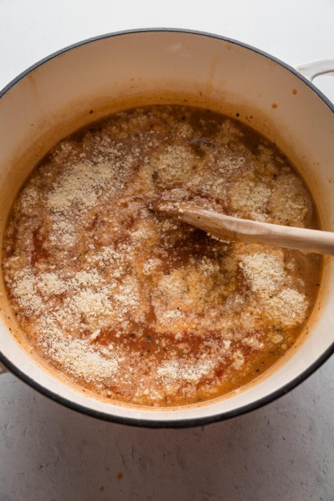 Parmesan and crushed tomatoes added to a stockpot.