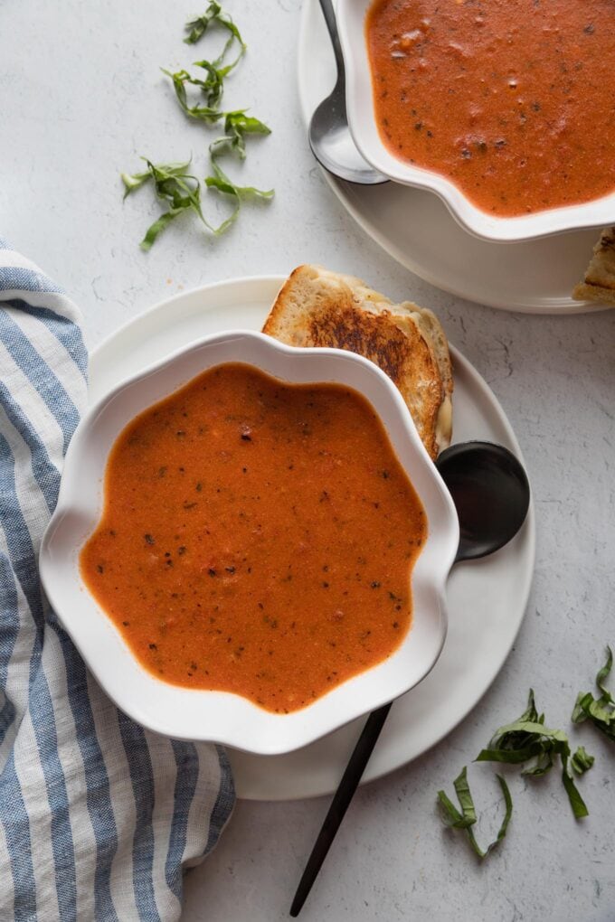 Countertop set with two bowls of a super quick and easy homemade tomato soup made with sun-dried tomato pesto for extra flavor.