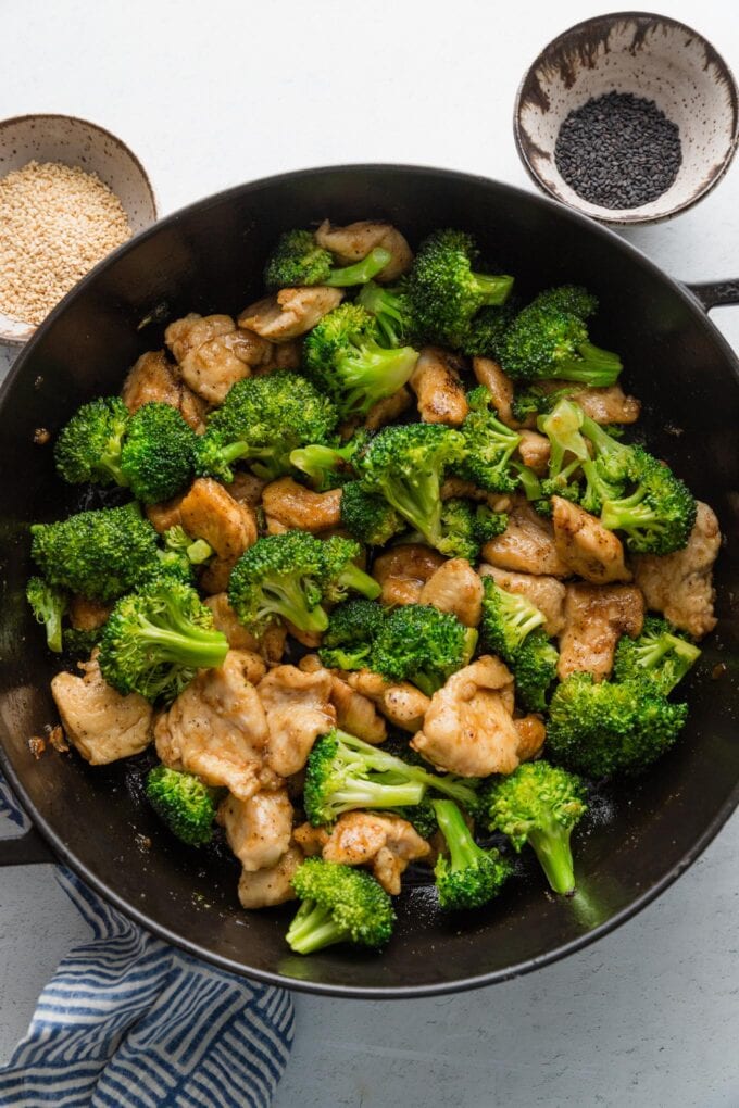 Overhead view of a large cast iron skillet full of Asian flavored chicken and broccoli.