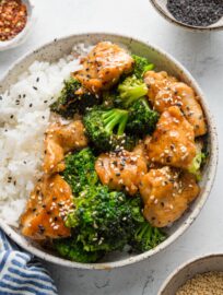 Bowl of Asian chicken and broccoli with rice and sesame seeds.