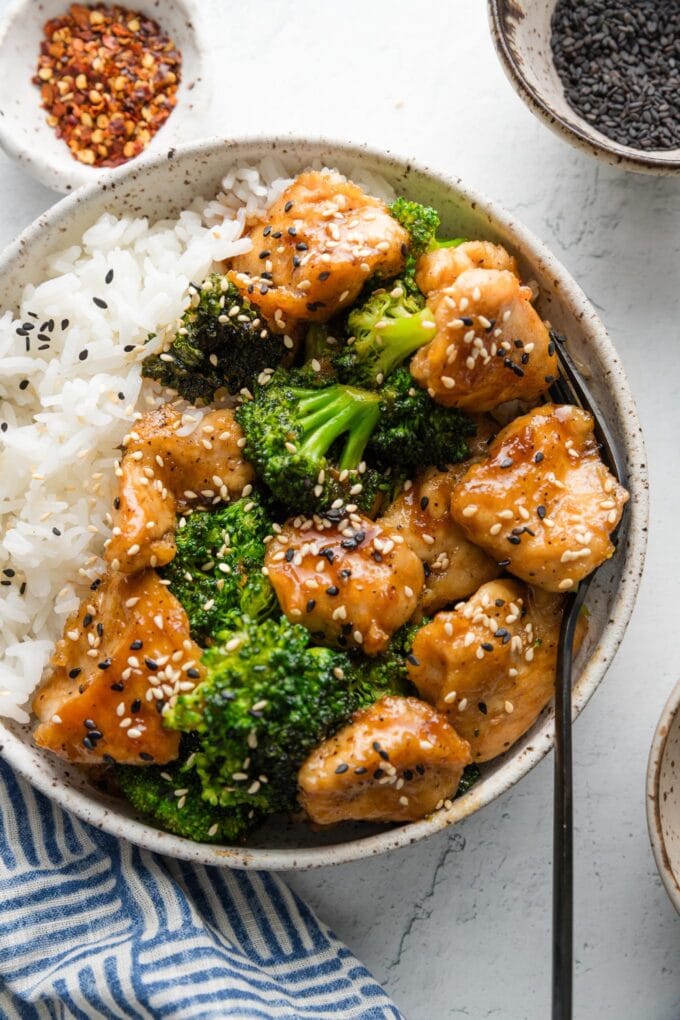Low bowl with a serving of Asian chicken and broccoli served with rice and sesame seeds.