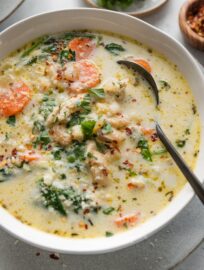 Close up of a bowl of creamy chicken soup with a rich yet light broth, carrots, onion, spinach, ditalini, and Cannellini beans.
