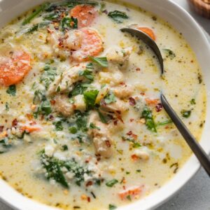Close up of a bowl of creamy chicken soup with a rich yet light broth, carrots, onion, spinach, ditalini, and Cannellini beans.