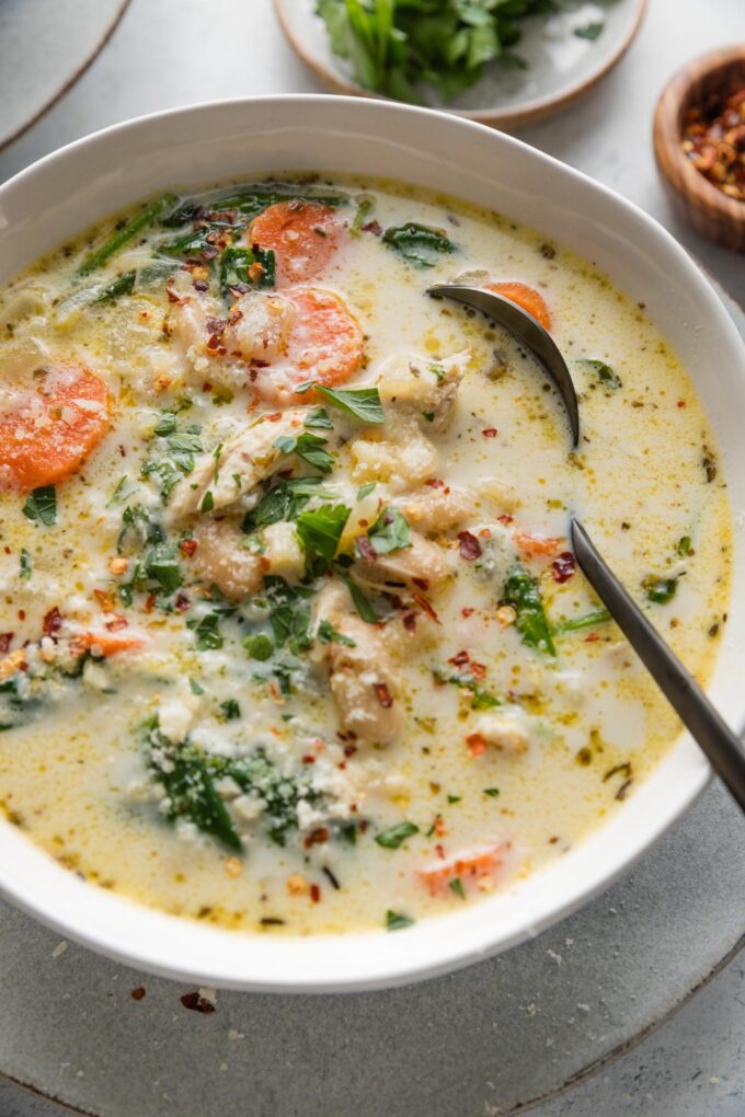 Close up of a bowl of creamy chicken soup with a rich yet light broth, carrots, onion, spinach, ditalini, and Cannellini beans.