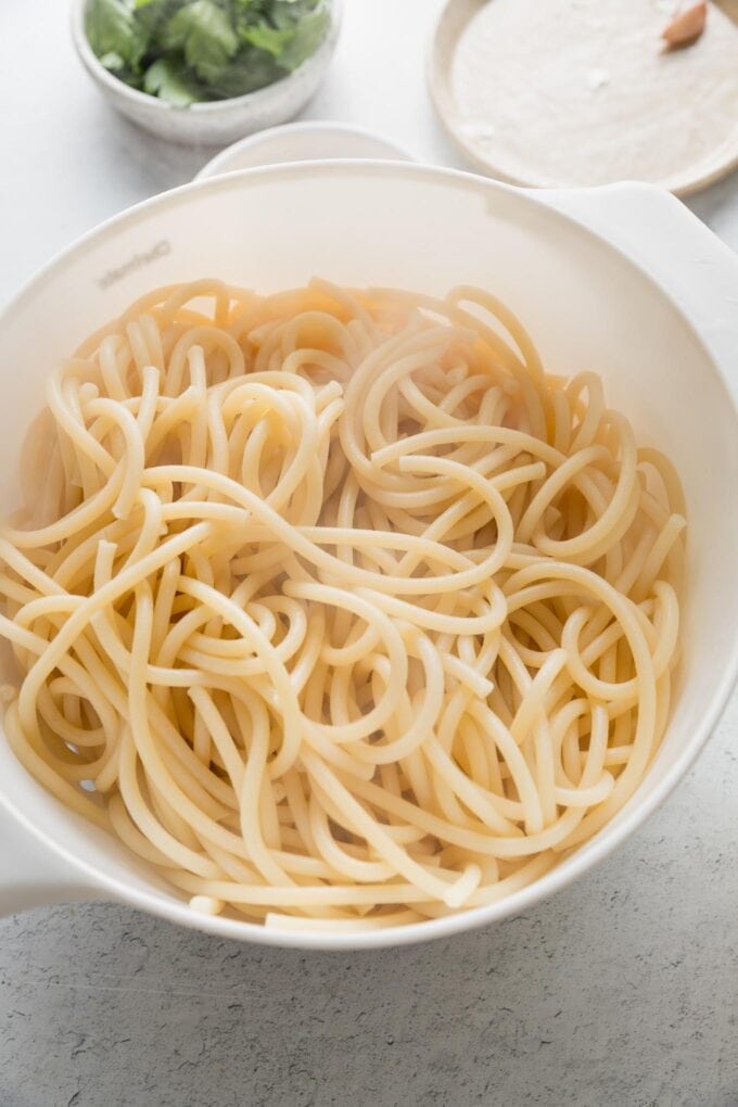 Drained bucatini resting in a strainer.