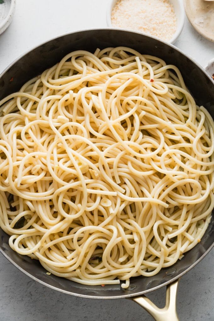 Bucatini added to a large skillet with an emulsified sauce.