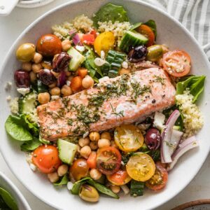 Bowl with couscous, Greek baked salmon, and a big chickpea vegetable salad.