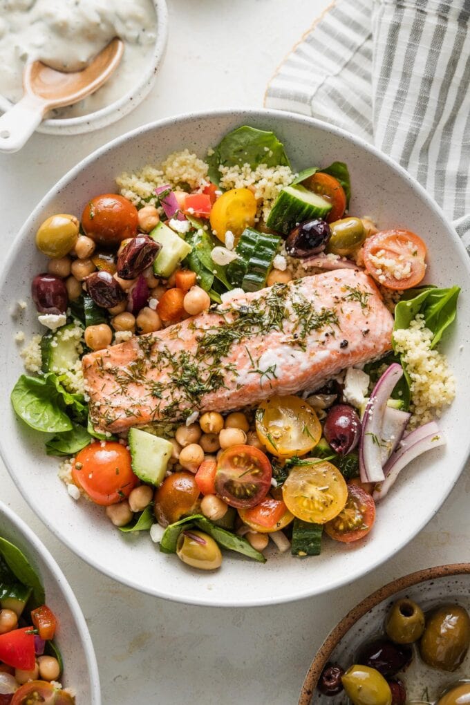 Bowl with couscous, Greek baked salmon, and a big chickpea vegetable salad.