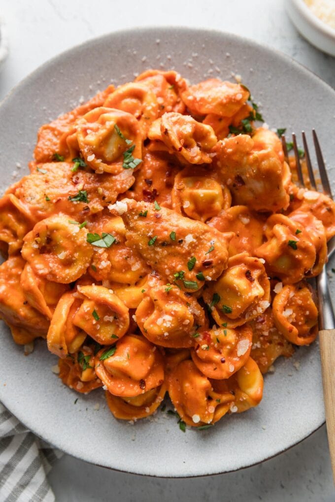 Close up of Italian chicken tortellini in tomato sauce piled high on a plate.
