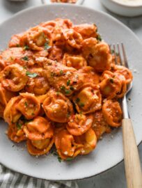 Plate filled bites of chicken and cheese-filled tortellini simmered in a light homemade tomato cream sauce infused with Italian herbs.