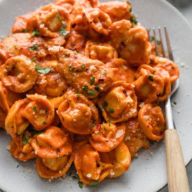 Plate filled bites of chicken and cheese-filled tortellini simmered in a light homemade tomato cream sauce infused with Italian herbs.