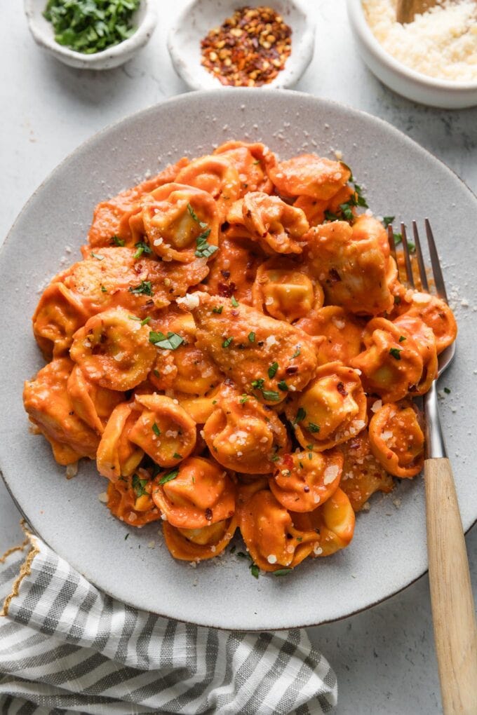 Overhead view of a dinner plate loaded with Italian chicken and tortellini in a homemade tomato cream sauce.