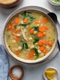 Two bowls of white bean gnocchi soup with chicken sitting on a kitchen countertop.
