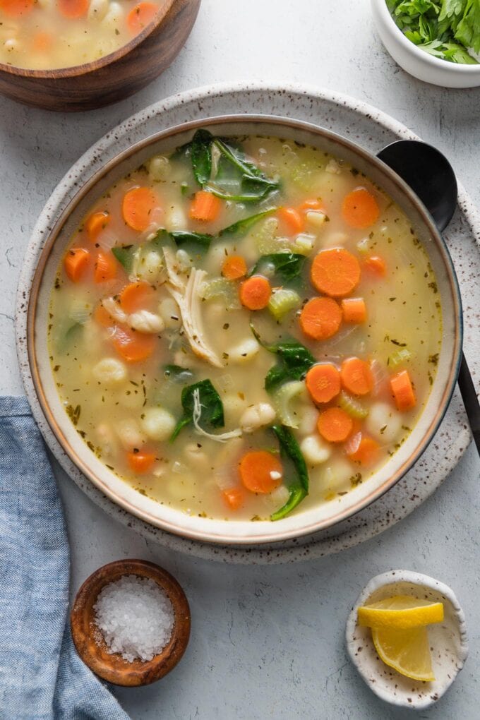 Two bowls of white bean gnocchi soup with chicken sitting on a kitchen countertop.