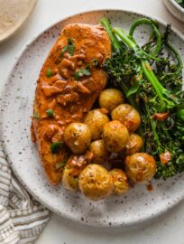Dinner plate of creamy paprika chicken served with roasted baby potatoes and broccolini.