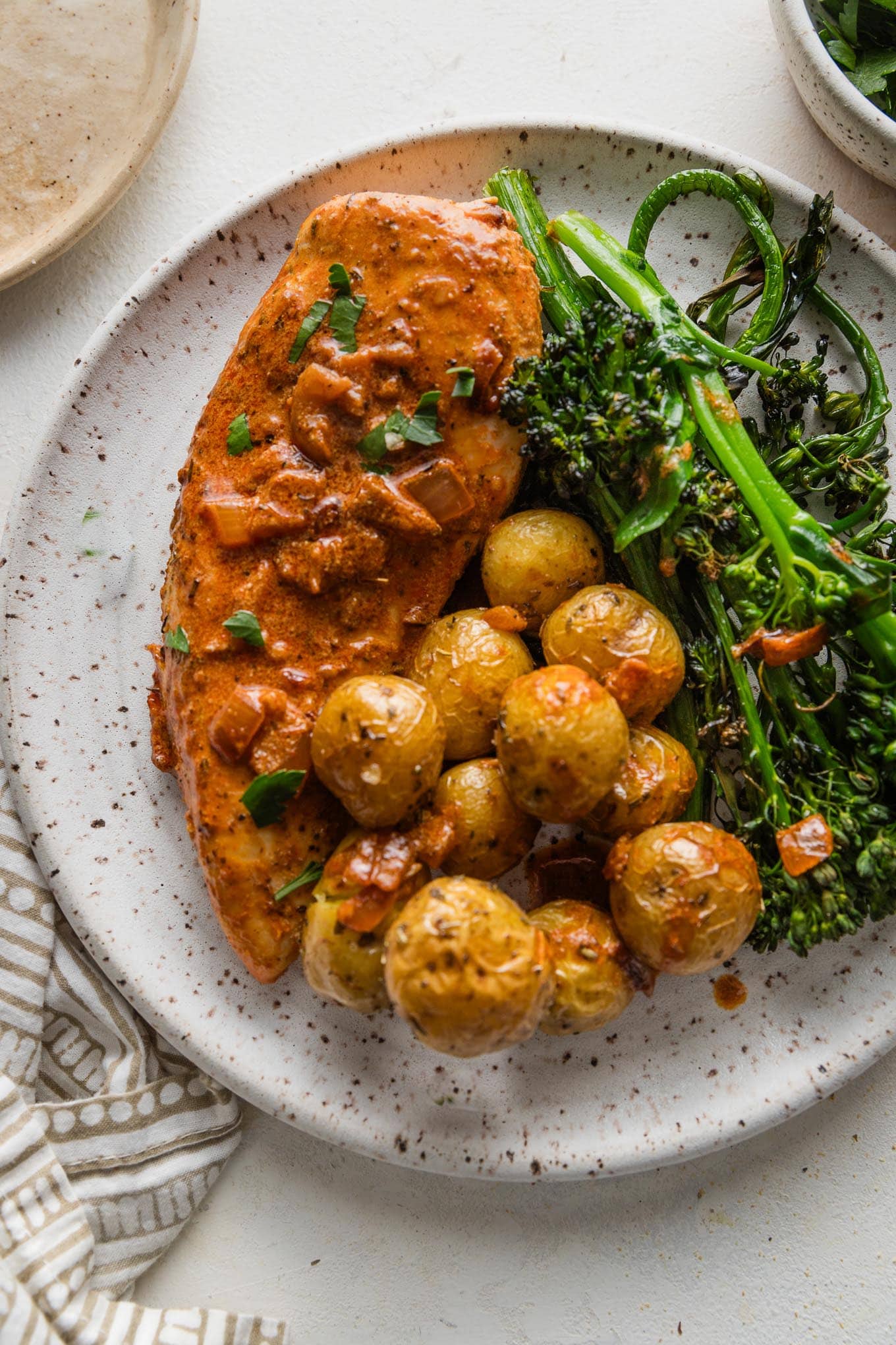 Dinner plate of creamy paprika chicken served with roasted baby potatoes and broccolini.