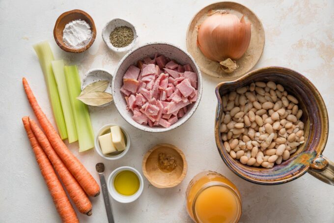 Landscape-oriented photo of all the ingredients for an easy ham and white bean soup with celery, carrots, and onion.