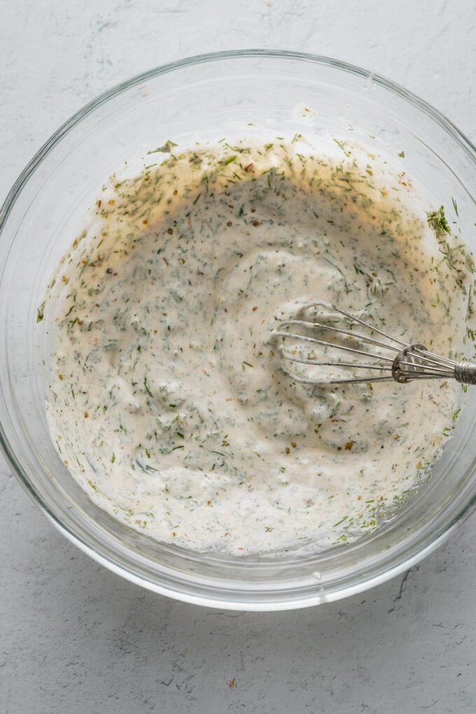 Greek yogurt-based dressing whisked together in a glass prep bowl.
