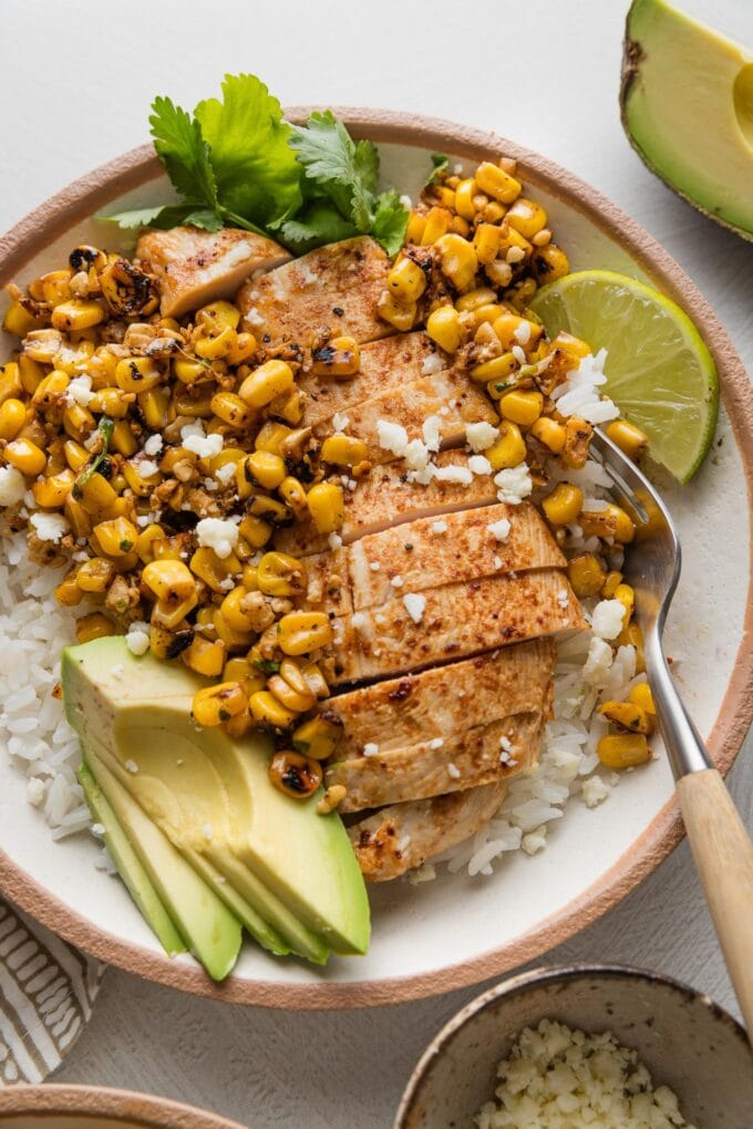 Street corn chicken and rice bowl with avocado, cilantro, and lime.