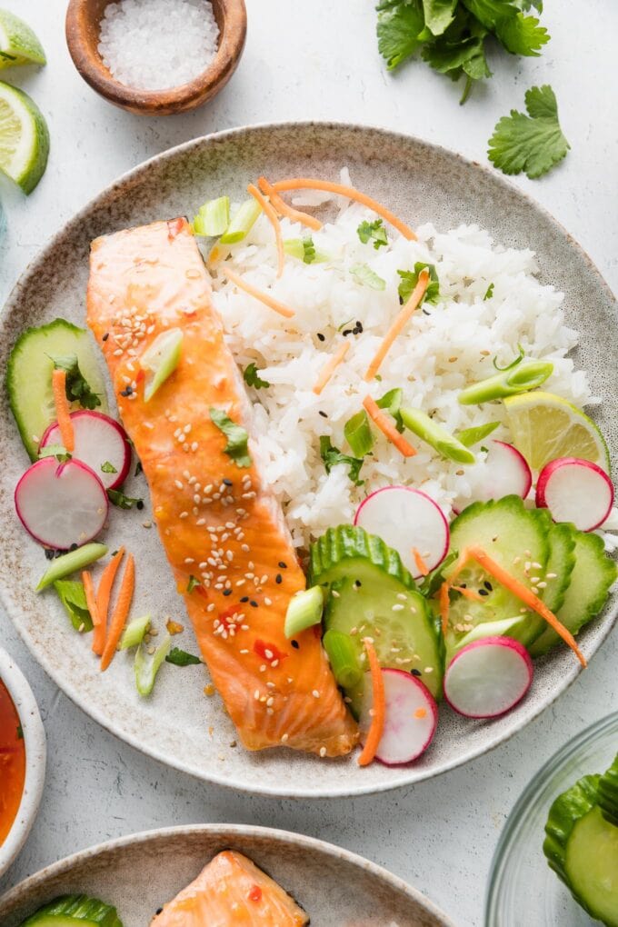 Plate of Thai sweet chili lime salmon with rice and lots of fresh veggies.