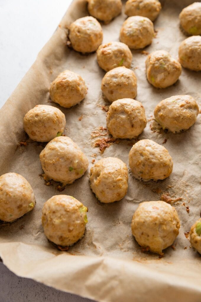 Just-baked and golden brown chicken meatballs on a rimmed baking sheet.