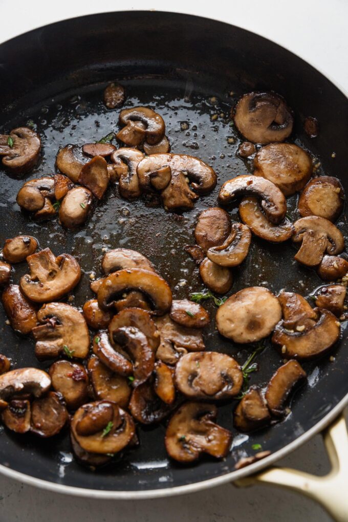 Richly browned sliced mushrooms in a pan.