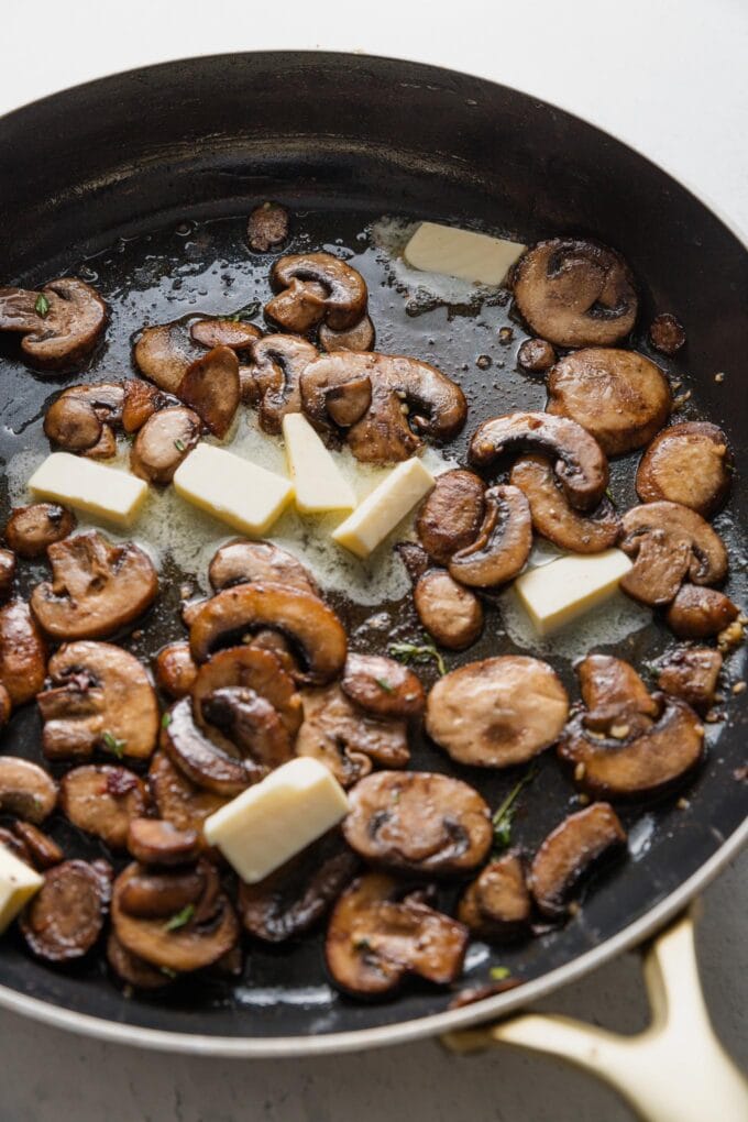 Garlic, thyme, and butter added to skillet with mushrooms.