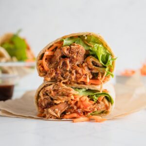 BBQ chicken wrap cut open to reveal the tender shredded chicken, crisp green leaf lettuce, and carrots inside.