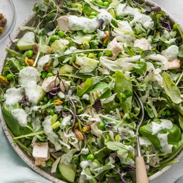 Large bowl full of a green goddess salad with homemade dressing and chicken.