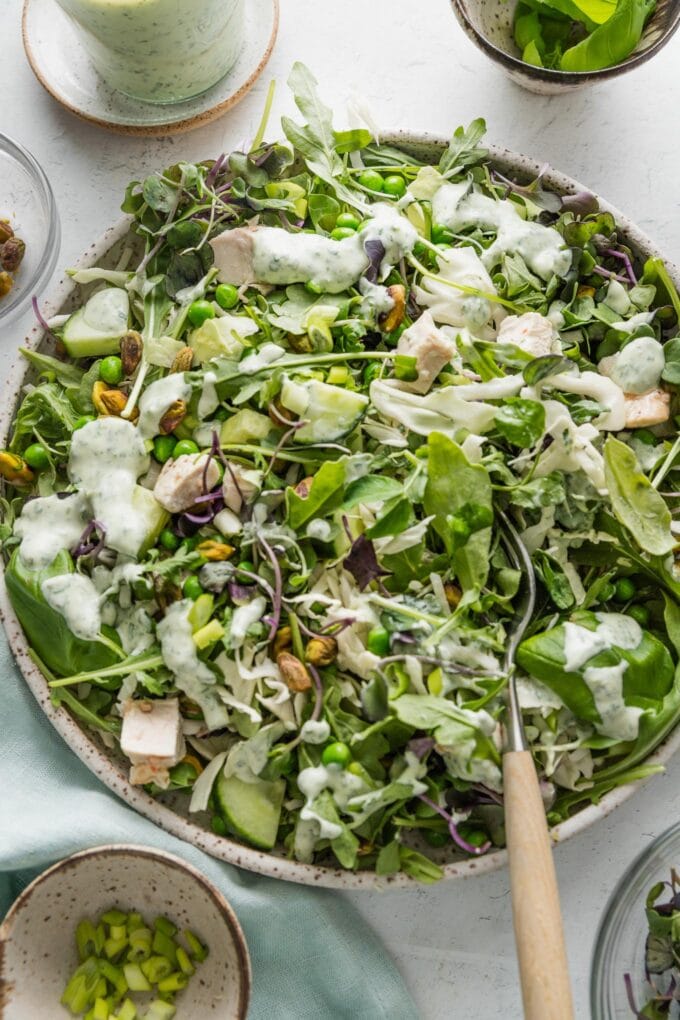 Large bowl full of a green goddess salad with homemade dressing and chicken.