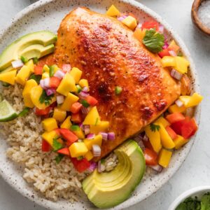 Dinner plate with honey lime baked salmon, mango salsa, and sliced avocado served over brown rice.