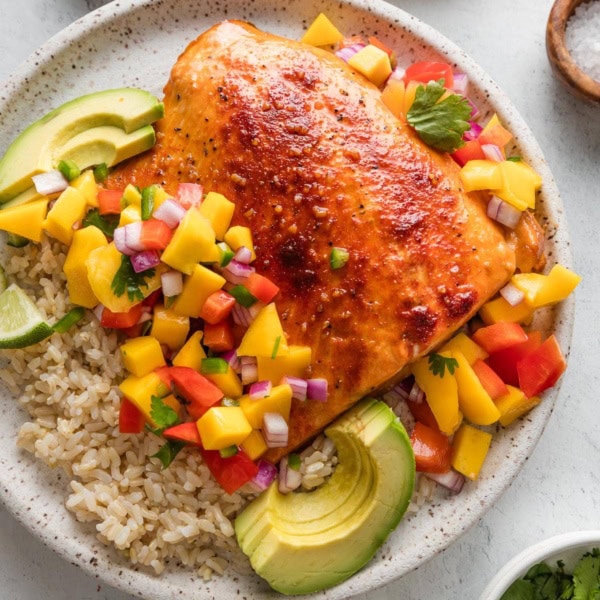 Dinner plate with honey lime baked salmon, mango salsa, and sliced avocado served over brown rice.