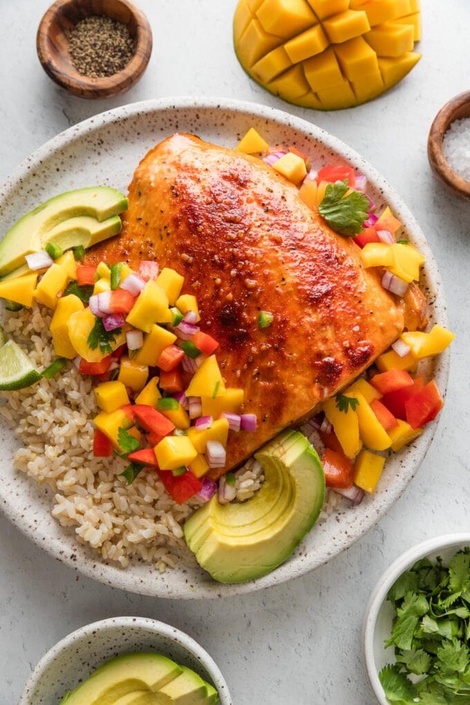 Dinner plate with honey lime baked salmon, mango salsa, and sliced avocado served over brown rice.