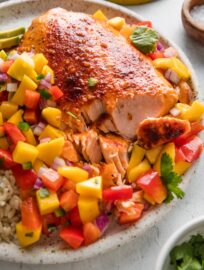 Plates of this rainbow-hued honey lime salmon with mango salsa will bring smiles and satisfaction all around. The salmon is baked for maximum tenderness and hands-off convenience; it quietly absorbs a luscious honey citrus glaze while you are free to toss together the dreamiest topping of sweet mango, crisp bell pepper, and fresh cilantro. Serve on its own or over rice or greens for the happiest, healthiest dinner.