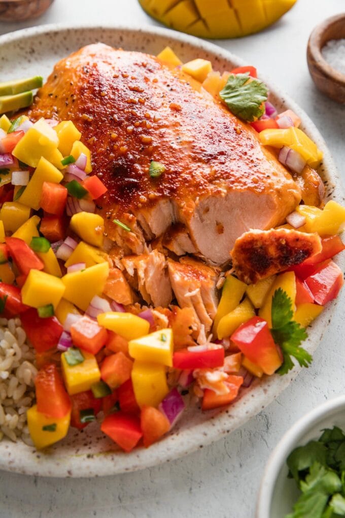 Plates of this rainbow-hued honey lime salmon with mango salsa will bring smiles and satisfaction all around. The salmon is baked for maximum tenderness and hands-off convenience; it quietly absorbs a luscious honey citrus glaze while you are free to toss together the dreamiest topping of sweet mango, crisp bell pepper, and fresh cilantro. Serve on its own or over rice or greens for the happiest, healthiest dinner.