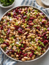 Italian bean salad with red onion and celery in a large ceramic serving bowl.