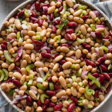 Italian bean salad with red onion and celery in a large ceramic serving bowl.