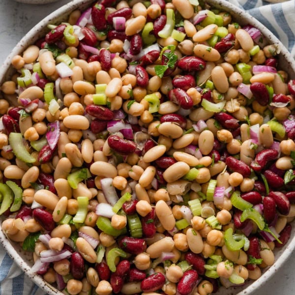 Italian bean salad with red onion and celery in a large ceramic serving bowl.