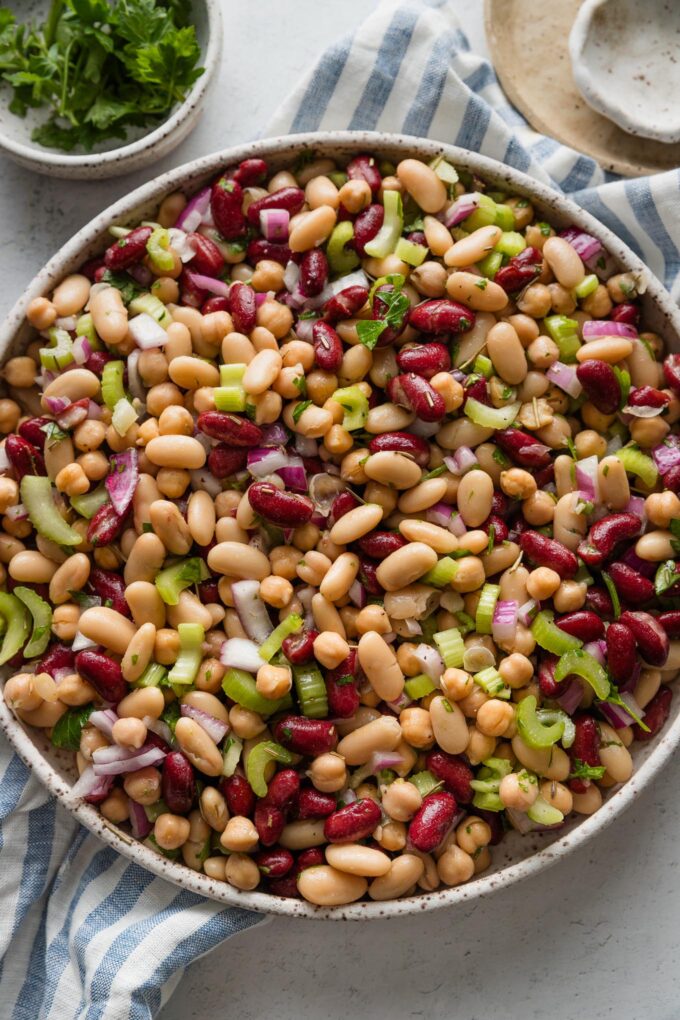 Italian bean salad with red onion and celery in a large ceramic serving bowl.