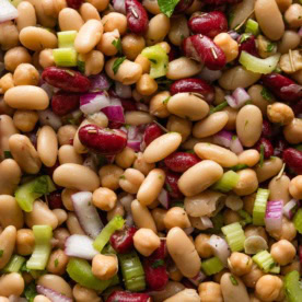 Close up of an Italian bean salad with three kinds of beans, chopped celery, red onion, and parsley.