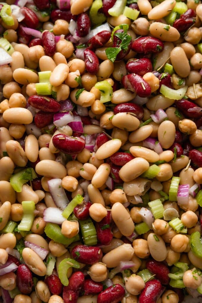 Close up of an Italian bean salad with three kinds of beans, chopped celery, red onion, and parsley.