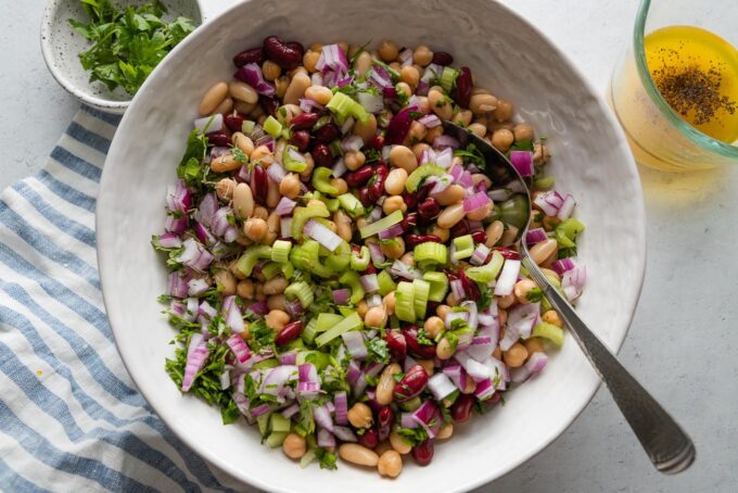 Beans, onion, celery, and parsley tossed in a large bowl.
