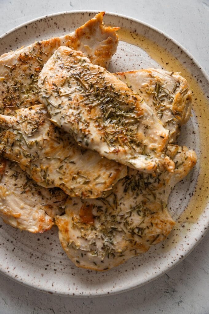 Seared chicken breasts returned to a clean plate to rest.