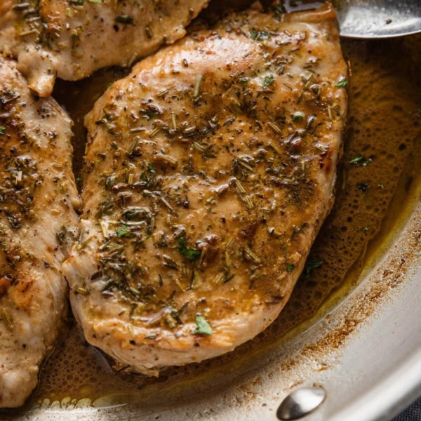 Chicken breast in a skillet with an herb and balsamic pan sauce.