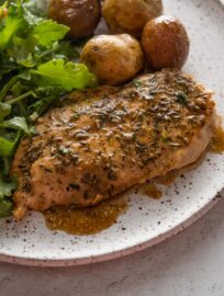 Balsamic skillet chicken breast plated with roast baby potatoes and salad greens.