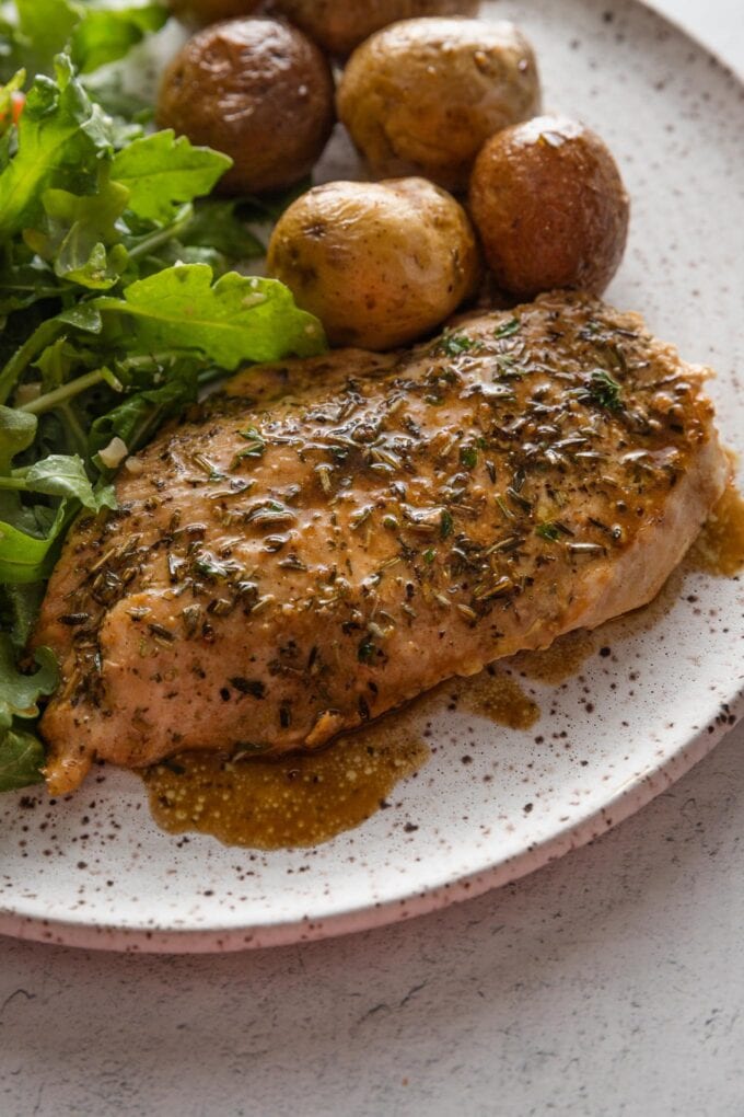 Balsamic skillet chicken breast plated with roast baby potatoes and salad greens.