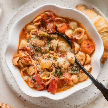 Bowl full of easy minestrone soup with chicken topped with Parmesan and fresh parsley.