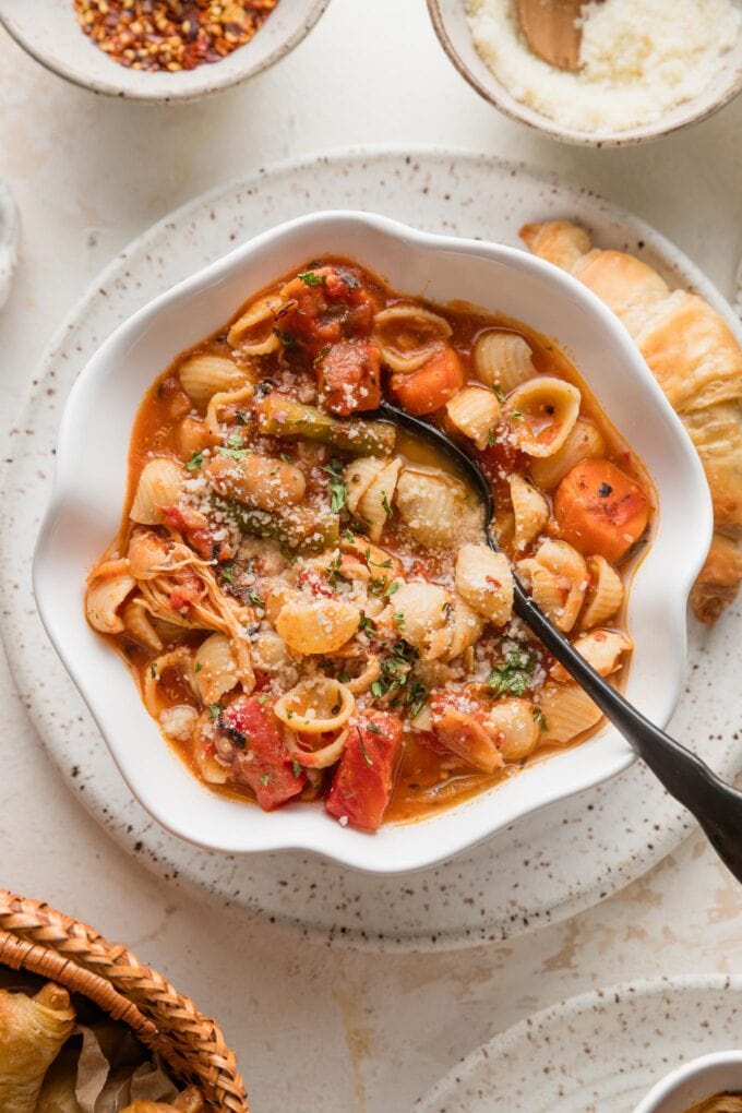 Bowl full of easy minestrone soup with chicken topped with Parmesan and fresh parsley.