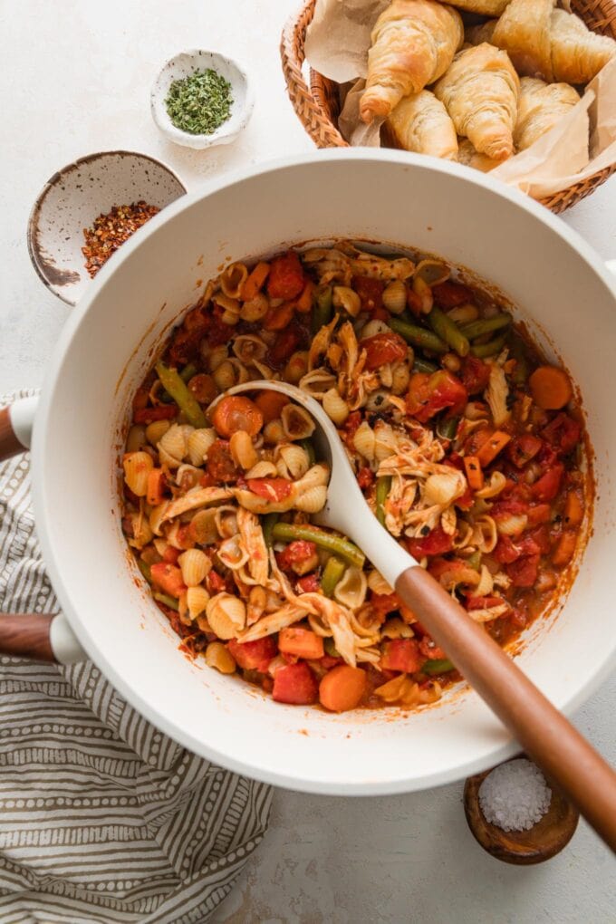 Chicken minestrone soup finished in a stock pot with a ladle ready to scoop out a portion.